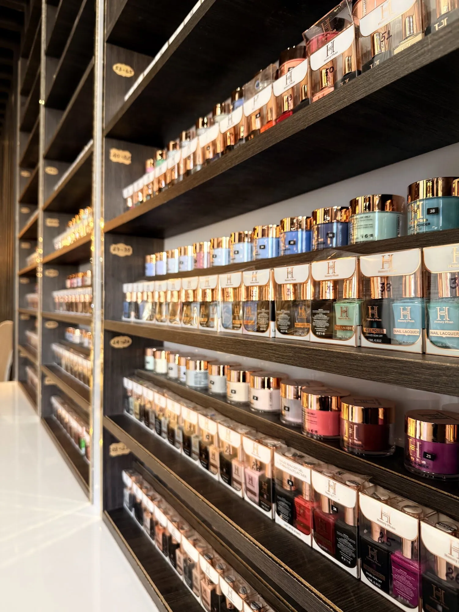 Shelves of dip powder jars in every shade lining a wall at Aria Nail Bar Fashion Square.