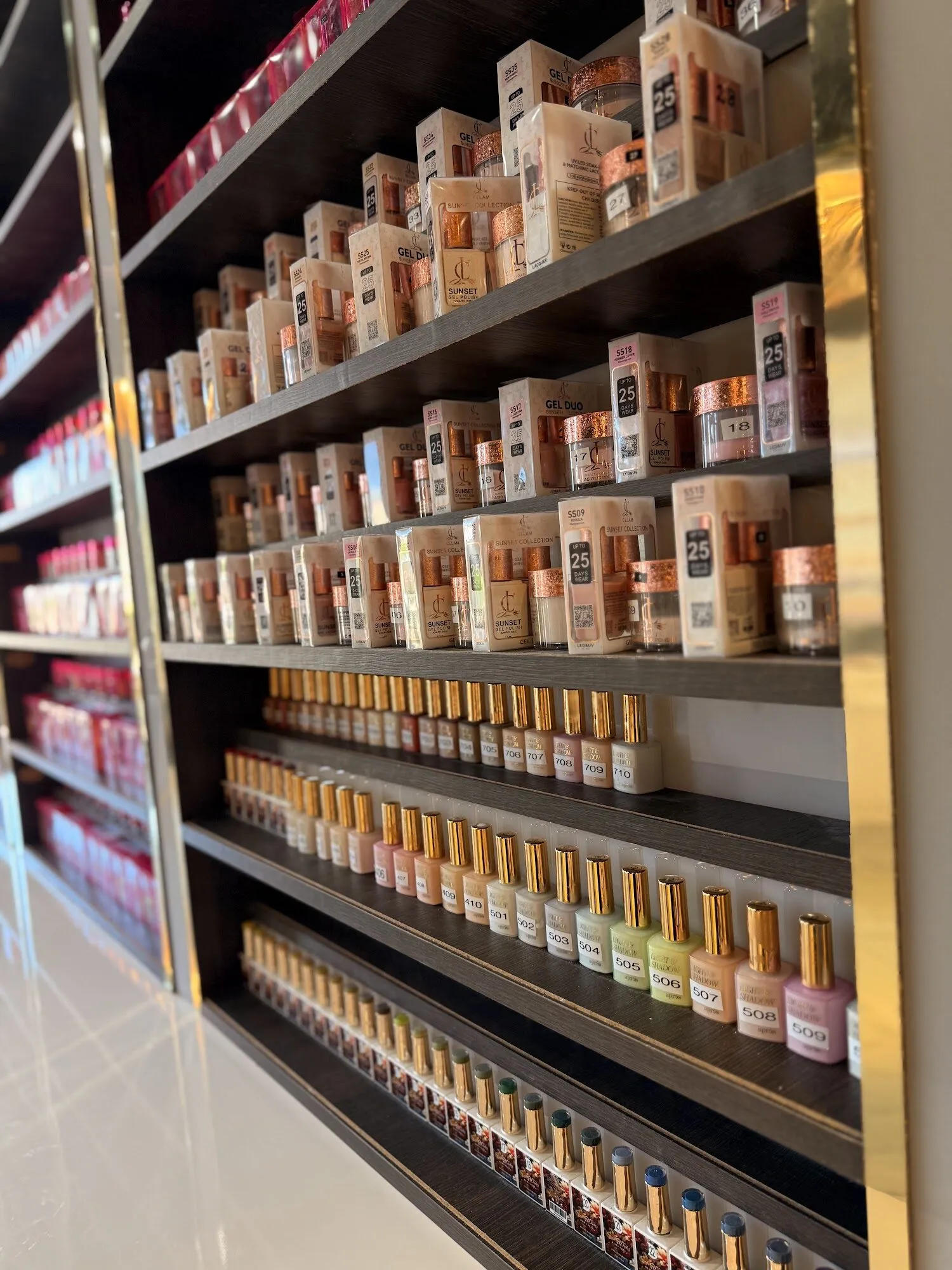 Gold-trimmed shelves stacked with nail polish and gel colors at Aria Nail Bar Fashion Square.