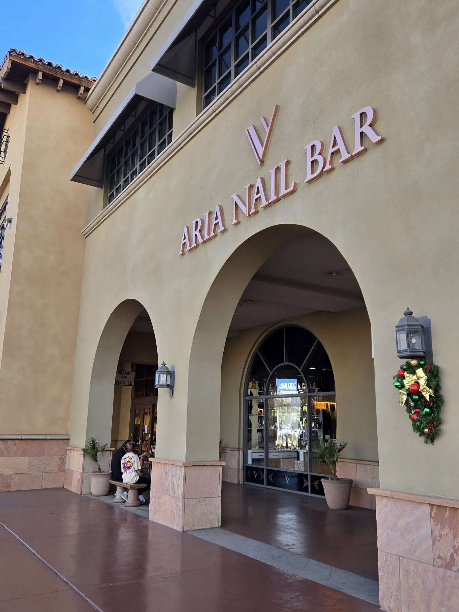 The arched storefront of Aria Nail Bar Fashion Square on Camelback Road, its name in letters above the entrance.