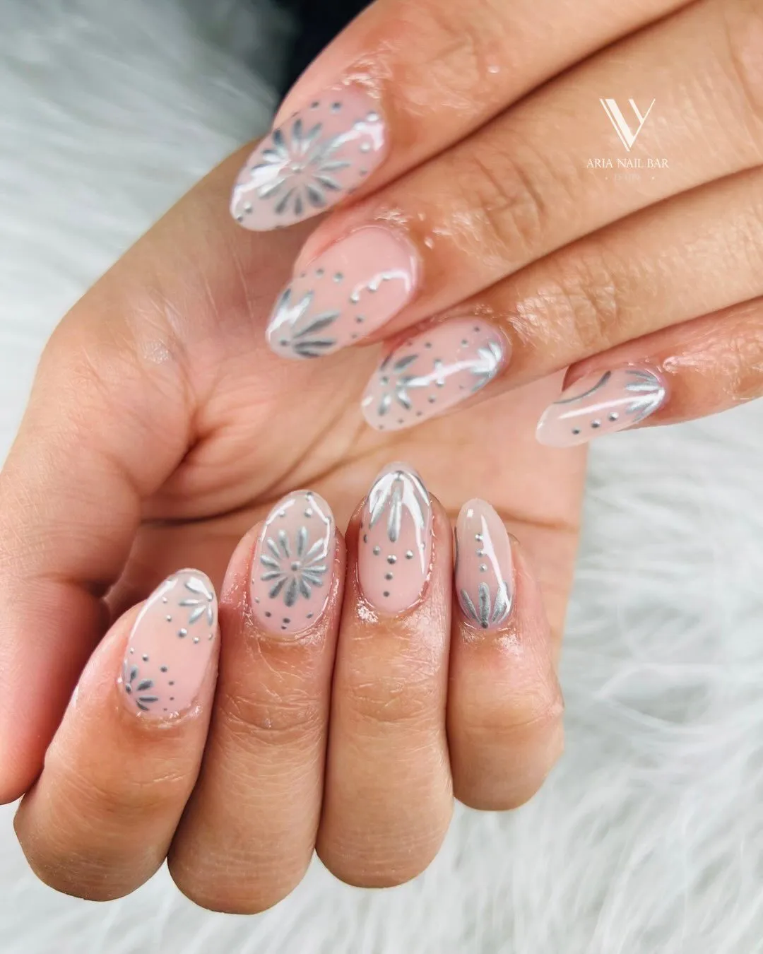 Nude almond nails with delicate silver botanical line art and dots.