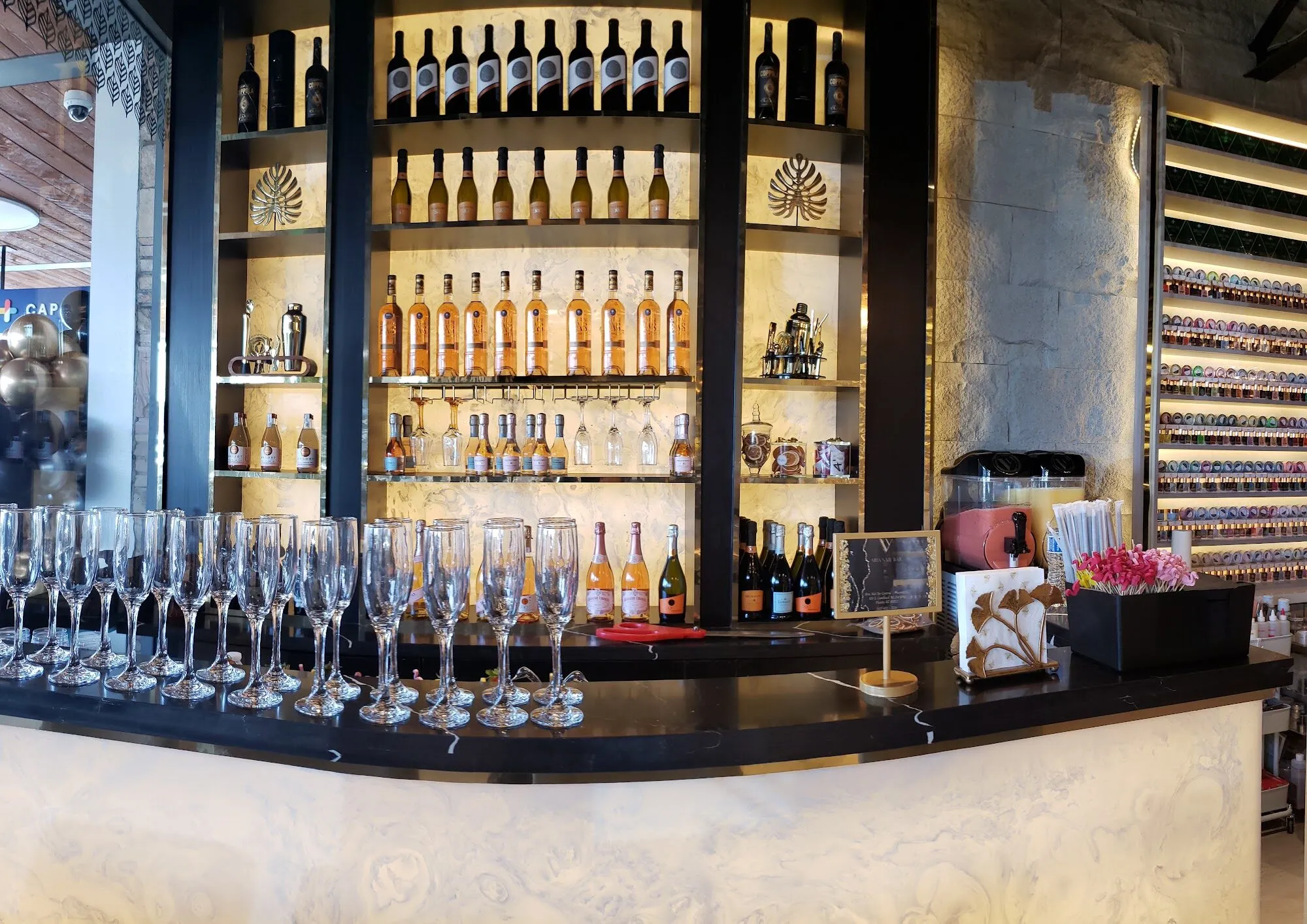 The champagne bar at Aria Nail Bar Phoenix Central, lined with flutes and backlit bottles.
