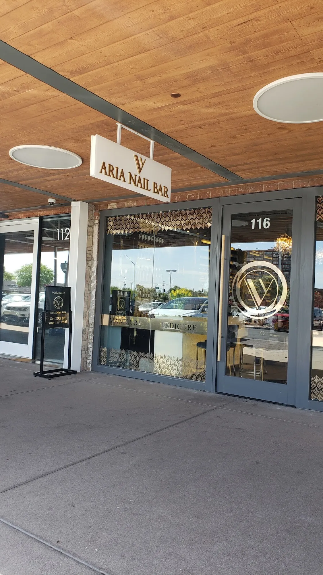 The glass entrance door of Aria Nail Bar Phoenix Central, with the V mark on the door and the salon glowing inside.