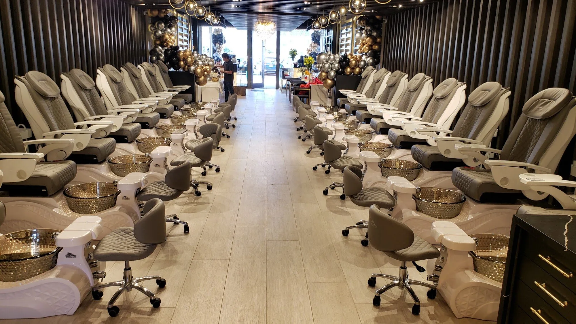 Rows of white pedicure chairs facing each other under warm lighting at Aria Nail Bar Phoenix Central.