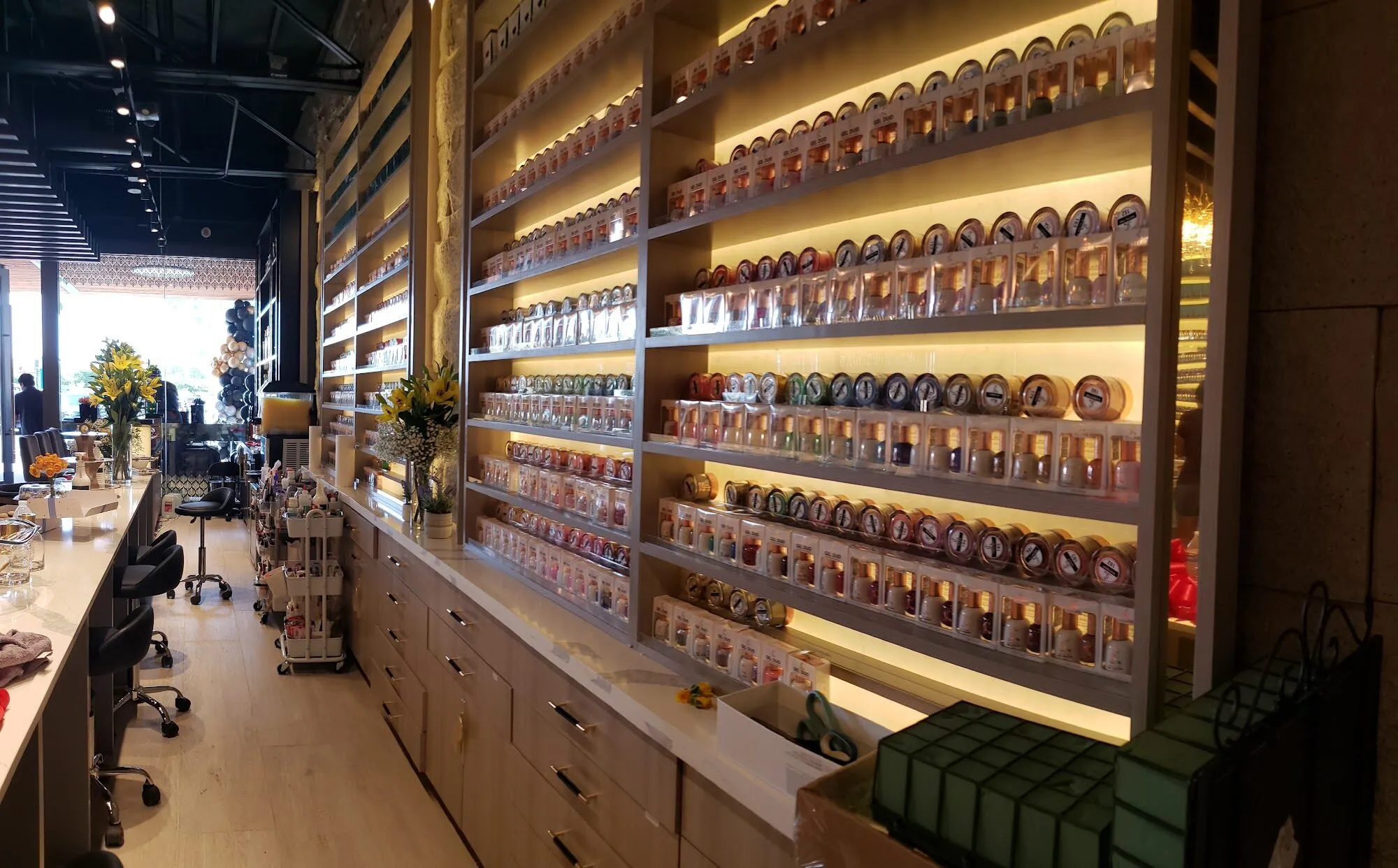 Backlit shelves of nail polish at Aria Nail Bar, arranged by shade.