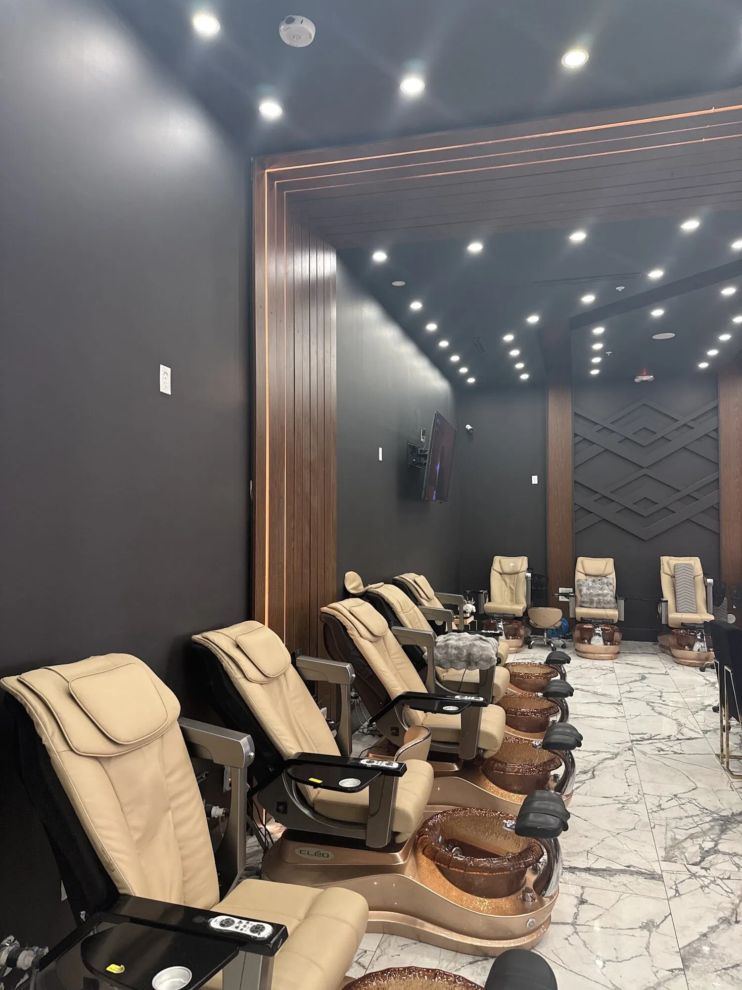 Cream leather pedicure chairs on marble floors with dark walnut walls at Aria Nail Bar Tempe.