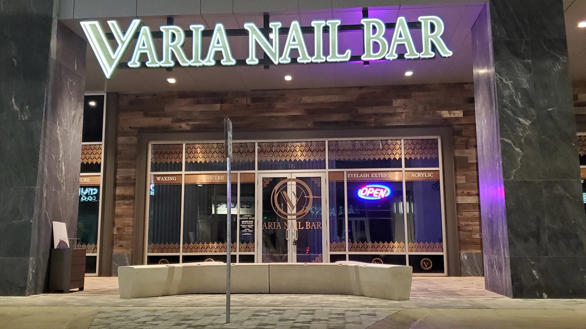 The storefront of Aria Nail Bar Tempe at night, its illuminated sign above the glass entrance on North Scottsdale Road.
